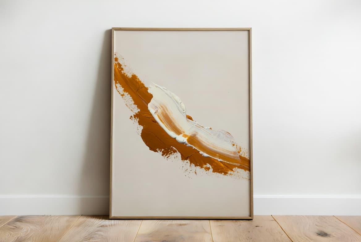 Abstract art print with ochre and cream brushstroke leaning against a white wall