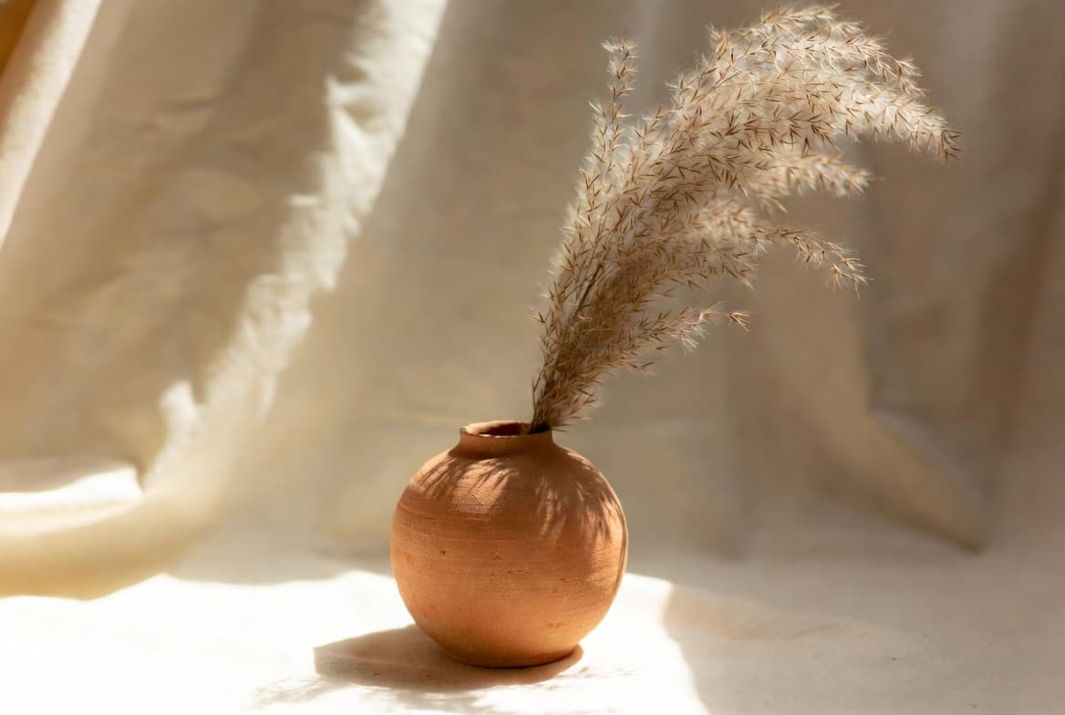 Terracotta bud vase with pampas grass on warm linen background